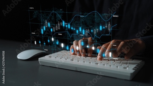 Fotografie Hands Typing on Keyboard with Digital Financial Graphs and Data Analytics on Screen in Background, Technology and Business Environment