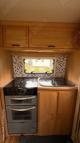 Cuadro en lienzo Compact caravan kitchen interior with wooden cabinetry, gas stovetop, sink and p