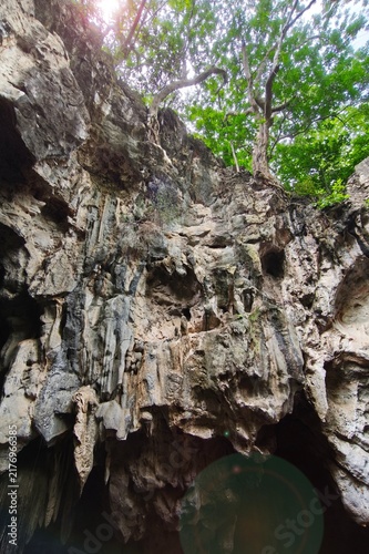Low angle view of a dark cave exit with sunlight streaming into the cave shaft.
