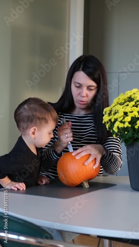 Mother helping son carve pumpkin