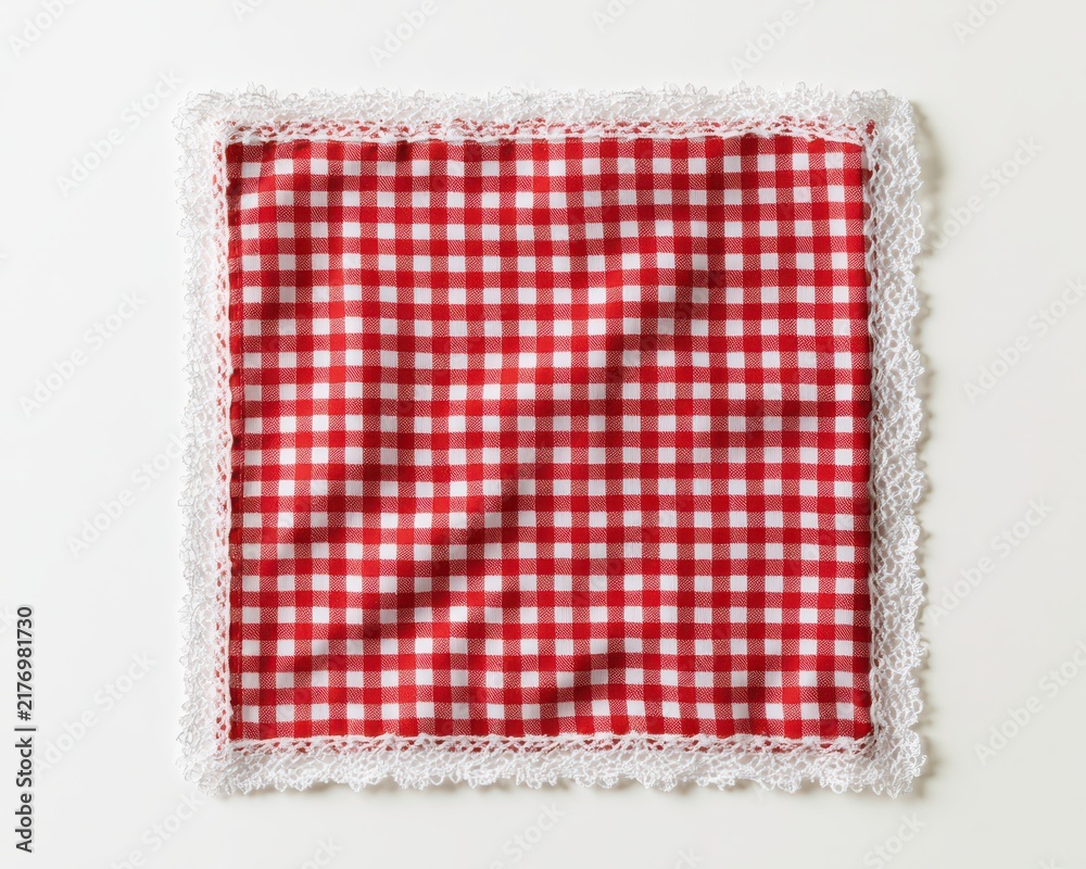 Fototapeta premium Red and white checkered fabric napkin with delicate lace trim isolated on white background