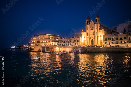 Facade of the Parish Church of Our Lady of Mount Carmel illuminated with reflections in the sea of ​​Balluta Bay, St. Julian's MALTA