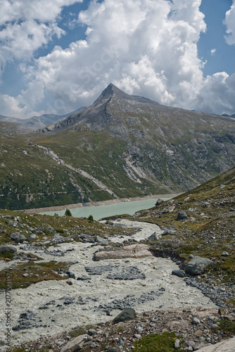 Wild mountain river, Mattmarksee dam and Stellihorn mountain peak in Pennine Alps in Switzerland