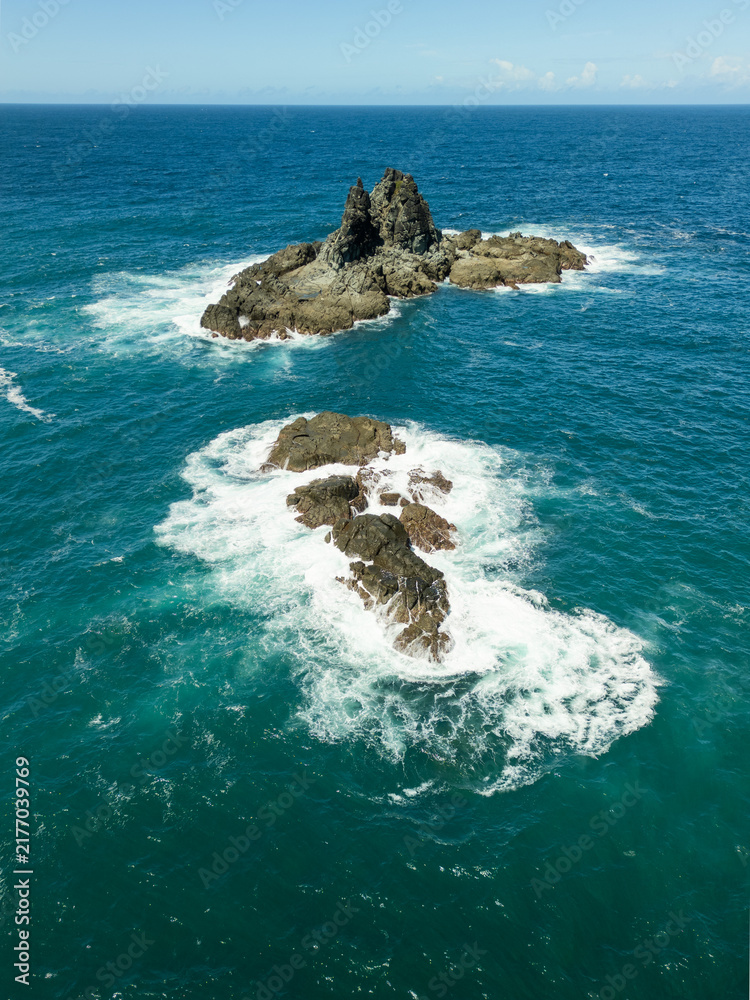 Obraz premium Wild Reef Outcrop Rising from Churning Turquoise Ocean Waves