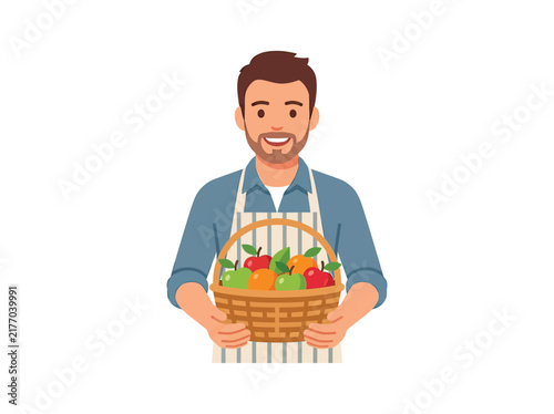 Smiling man holding a basket of fresh fruits wearing an apron