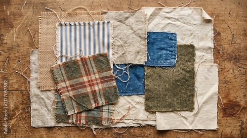 Rustic fabric swatches with loose threads on wooden surface
