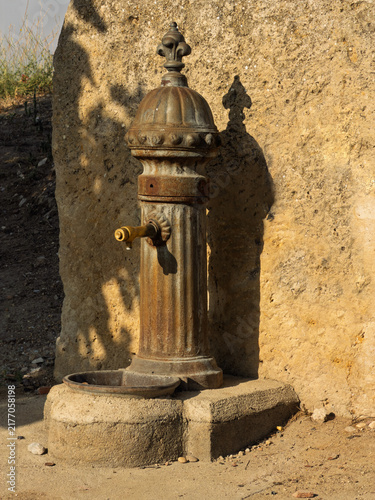 Vintage Outdoor Water Fountain Tap Against Stone Wall With Rusty Brass Spout And Basin