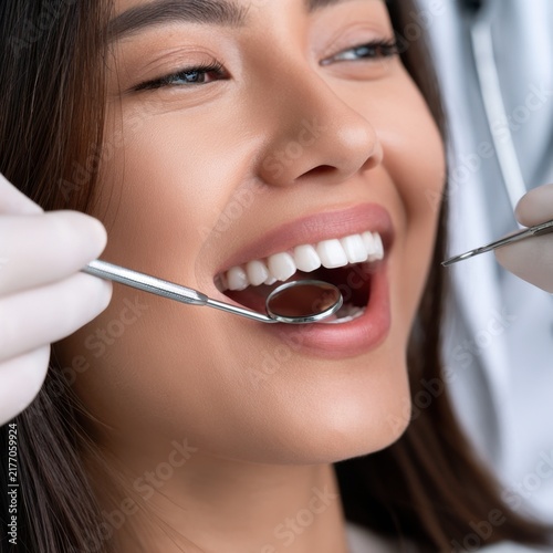 Smiling woman receiving a dental checkup with professional teeth examination tools for oral health and hygiene care at clinic