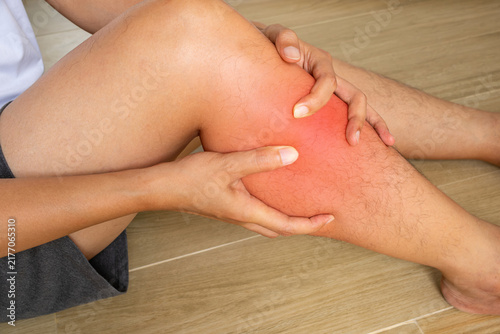 Foto Shin pain shown with hands supporting the lower leg and a red medical overlay