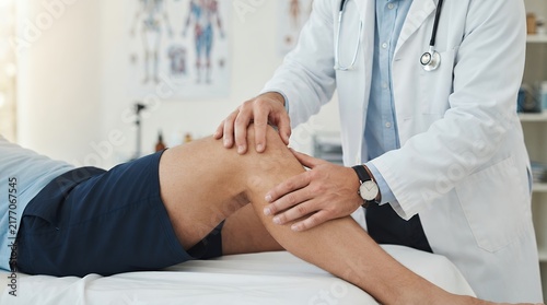 Orthopedic doctor examining patient knee, medical professional performing physical therapy, sports medicine specialist in clinic