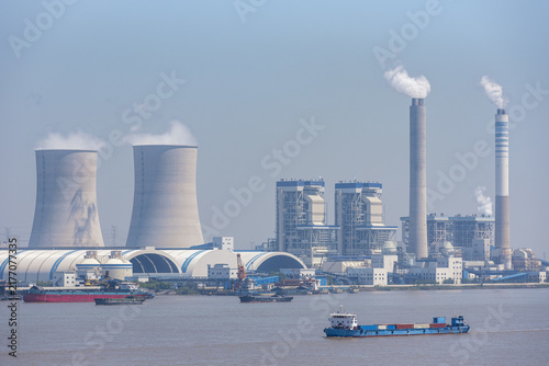 Foto Modern thermal power station located along the Yangtze River, China, with enormous cooling towers, exhaust stacks and industrial buildings visible from across the water