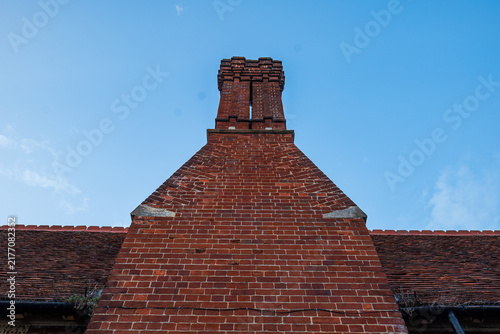 Low angle view of a tall traditional red brick chimney stack against a blue sky