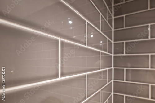 Close up perspective view of glossy grey subway tiles with white grout lines