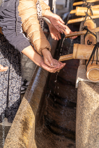 Closeup hands of people performing the ritual cleansing in Japan temple. This act is a symbolic purification of the body and mind, preparing oneself to approach the deities of Shinto religion