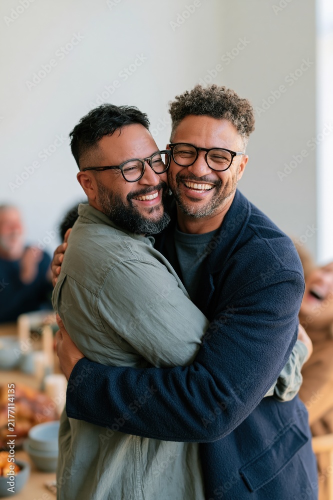 Obraz premium Two men hugging and laughing at a friendly gathering warm affectionate reunion moment for inclusive background