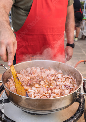 Traditional Traditional chopped Squid Stew being prepared with a wooden spoon in a pot on a stove in Spain. Squid Stew being prepared with a wooden spoon in a pot on a stove in Basque Country