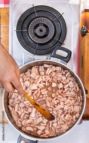 Traditional Traditional chopped Squid Stew being prepared with a wooden spoon in a pot on a stove in Spain. Squid Stew being prepared with a wooden spoon in a pot on a stove in Basque Country