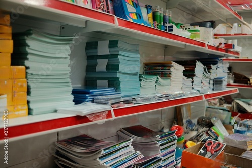 Wide view of a stationery store shelf filled with notebooks, paper, folders, and school supplies, highlighting organized retail inventory and everyday educational and office products.