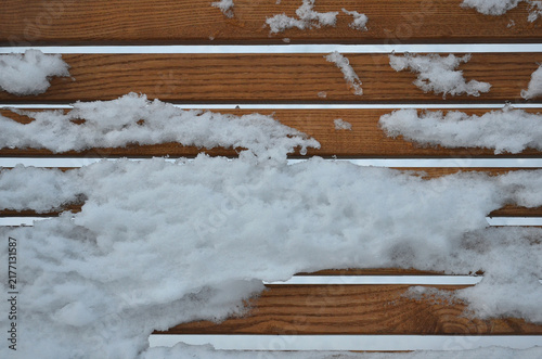 Bild auf Leinwand Snow covered brown yellow wooden bench boarders surface .