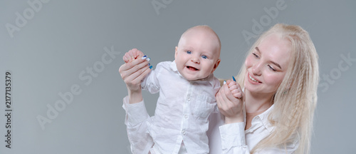 Konstfotografi Laughing caucasian baby boy held by his young mother in a wide studio crop with