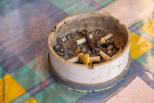 фотографія an ashtray containing cigarette butts and ash