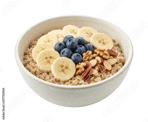 Healthy breakfast oatmeal bowl topped with sliced fresh banana blueberries and nuts