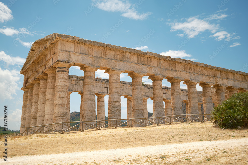 Fototapeta premium Panoramic side perspective of the ancient Greek Doric temple under a blue sky in Segesta, Sicily, Italy