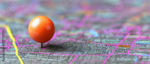 An orange spherical pushpin marks a textured map with vivid magenta and yellow lines, showcasing depth of field