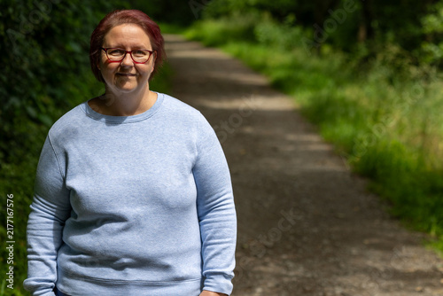 Woman smiling wearing glasses standing on park path