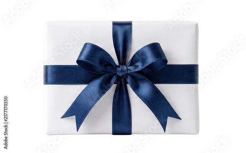 White gift box with navy blue satin ribbon bow on a bright surface during celebration