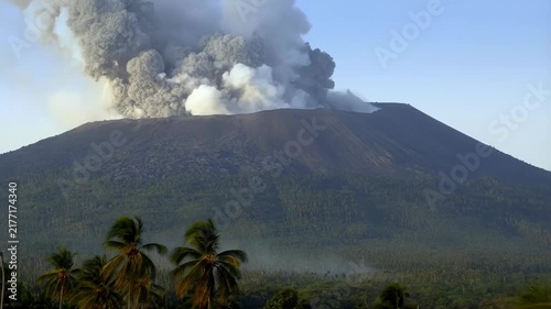 Volcano Erupting With a Massive Ash Plume Above a Tropical Forest and Palm Trees