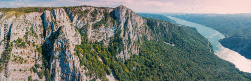 Foto Panoramic aerial view of dramatic limestone cliffs framing a wide Danube river winding through Iron Gate gorge and valleys at sunset