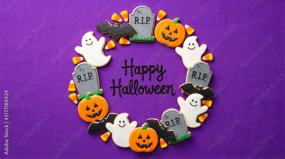 Fototapeta premium Happy halloween greeting card with a circular frame made of cute ghost pumpkin tombstone and bat cookies on a vibrant purple background