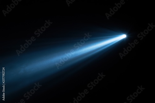 Macro photograph of a bright light beam isolated in darkness with dust motes and glow