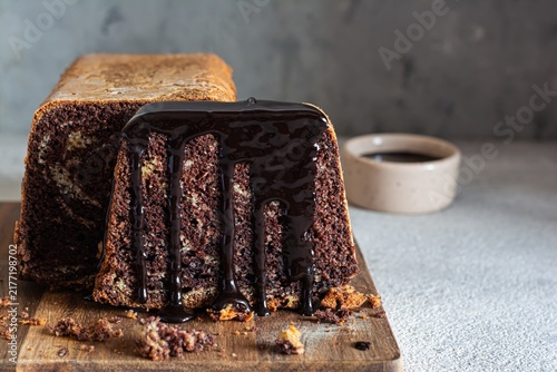 Chocolate marbled cake (biscuit) Zebra with chocolate icing on a wooden board on a gray background. Homemade dessert.