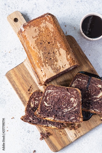 Chocolate marbled cake (biscuit) Zebra with chocolate icing on a wooden board on a gray background. Homemade dessert.