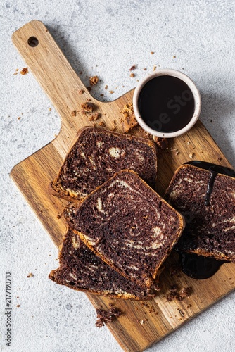 Chocolate marbled cake (biscuit) Zebra with chocolate icing on a wooden board on a gray background. Homemade dessert.
