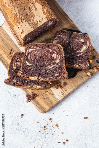 Chocolate marbled cake (biscuit) Zebra with chocolate icing on a wooden board on a gray background. Homemade dessert.