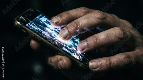 Close-up of hands interacting with a smartphone screen glowing in the dark
