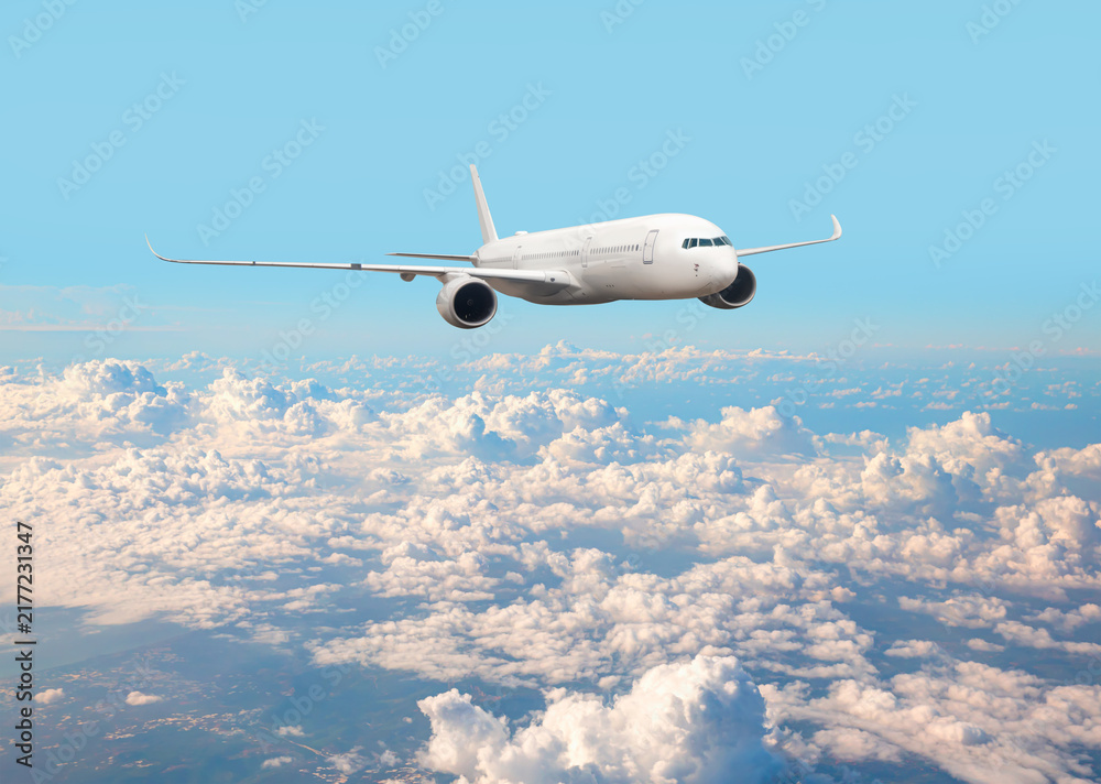 Naklejka premium White passenger airplane flying in the sky amazing clouds in the background - Travel by air transport