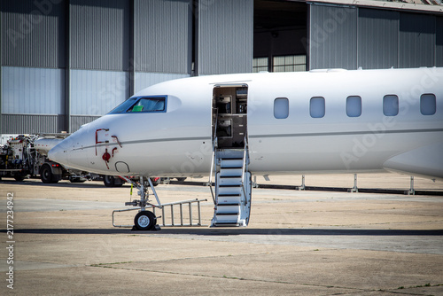 Private jet with open stair door on the tarmac of an airport.
