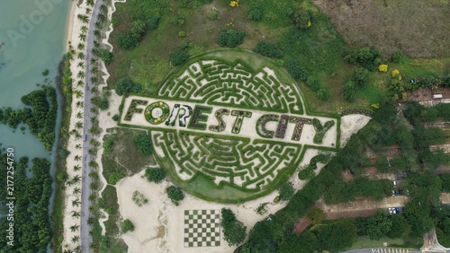 Aerial view of the Forest City maze garden with lush green hedges, a checkerboard pattern area, and surrounding coastal vegetation in Gelang Patah, Johor Darul Ta'zim, Malaysia.