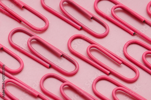 Rows of Pink Paperclips on Pink Background. Minimalist photo of multiple pink paperclips arranged in neat parallel rows on a pink surface. 