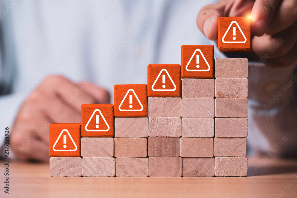 Obraz premium Risk management concept showing increasing warning signs on rising steps as a business professional identifies threats and manages growing risks through assessment, prevention and strategic planning.