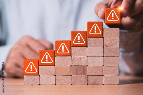 Obraz na płótnie Risk management concept showing increasing warning signs on rising steps as a business professional identifies threats and manages growing risks through assessment, prevention and strategic planning