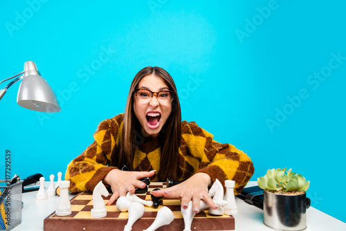 Obraz na plátne Frustrated woman shouting over a toppled chess game at a desk, expressing anger