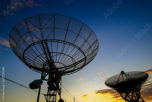 Radio telescope array at sunset, large satellite dish antennas against colorful twilight sky