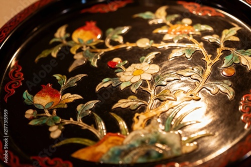 Intricate floral and fruit design on a black lacquered tray with gold and colorful inlay