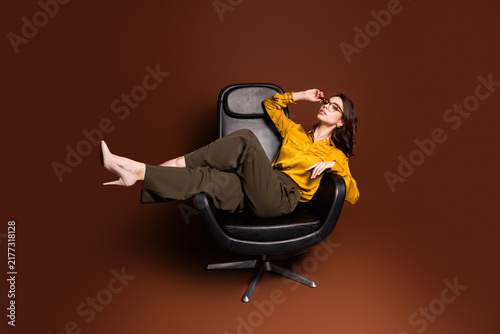 Quadro su tela Relaxed businesswoman reclining in modern black swivel chair wearing mustard yel