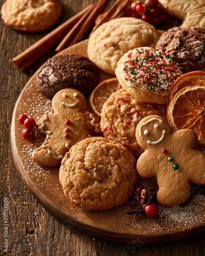 Assorted Christmas cookies on wooden platter with spices.